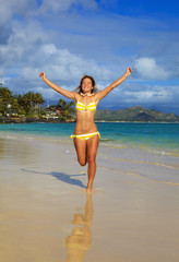 teenage girl runs along the beach at lanikai, hawaii