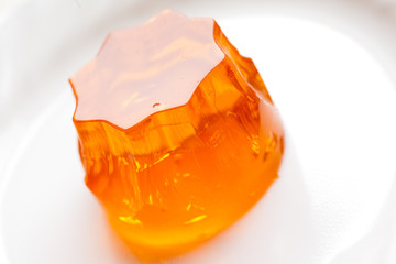 orange jello on white plate, close-up - obrazy, fototapety, plakaty