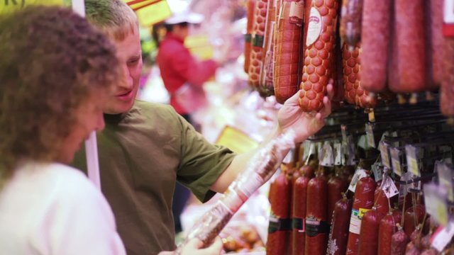 woman and man buying sausage in supermarket