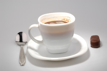 Cup of hot coffee with spoon and chocolate candy