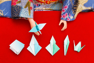 Fototapeta na wymiar Japanese doll in kimono showing the steps to fold a paper bird