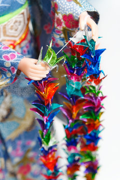 A Japanese Doll In Kimono Arranging Parts Of A Senbazuru