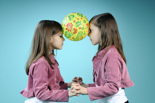 two sisters holding ball with their had