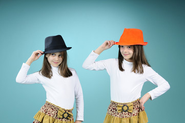 playful twin sisters dancing with hats