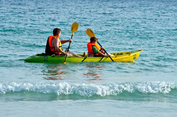 father and son are padelling with a canoe on open sea