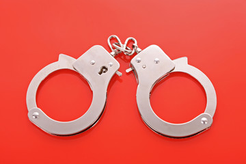 Grey handcuffs isolated on red background