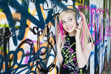 portrait of young woman with headphones at graffitti wall