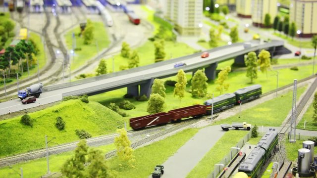 toy train bring cargo wagon on rail in toy city among highway