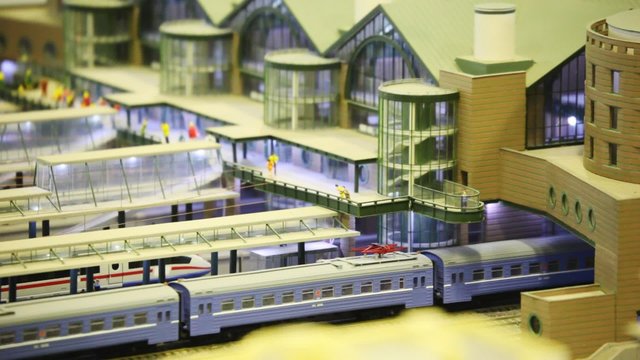 toy trains stand on platforms in passenger station with people