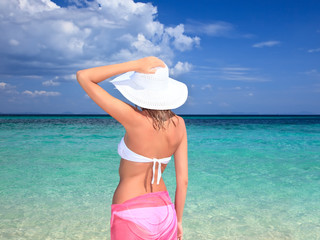 Fototapeta na wymiar woman with hat standing on the beach