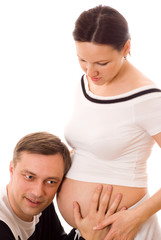 man leaned against the stomach of a pregnant wife on a white bac