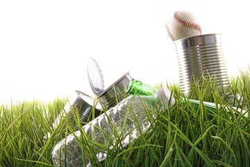 Empty food cans, bottles and baseball in grass