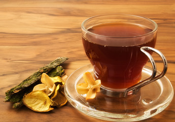 A cup of herbal tea and dried plants, wood table
