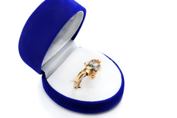 gold ring with blue topaz in a box on a white background
