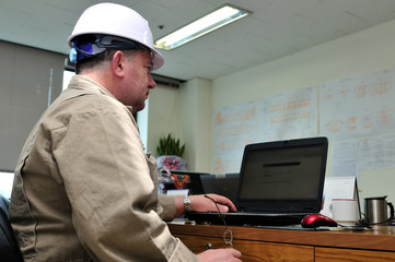 Engineer in helmet, working in office