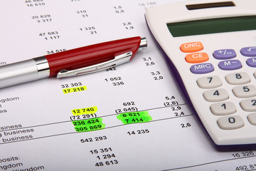 White calculator and a red pen on a financial report