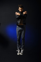 young man style jumping posing on blue light background