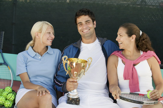 tennis players sitting at tennis court man holding trophy front view portrait