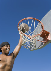 young man dunking basketball into hoop
