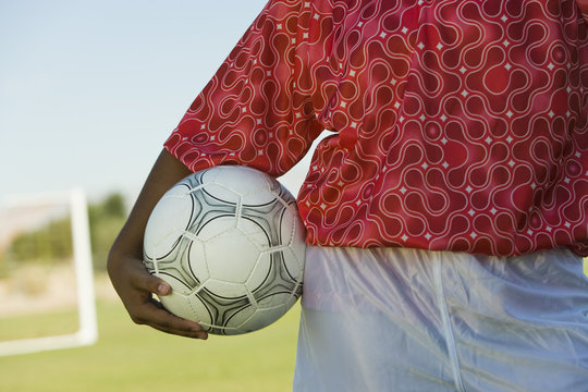 girl (13-17) holding soccer ball mid section