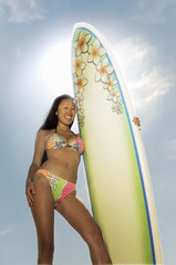 female surfer standing holding surfboard outdoors low angle view