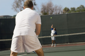 tennis player on court waiting for serve back view