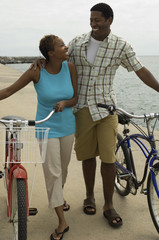 Obraz premium couple walking with bicycles on beach