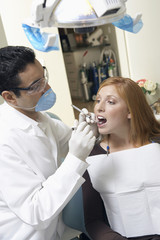 dentist examining young womans teeth in surgery