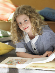 elementary schoolgirl reading book lying on floor portrait