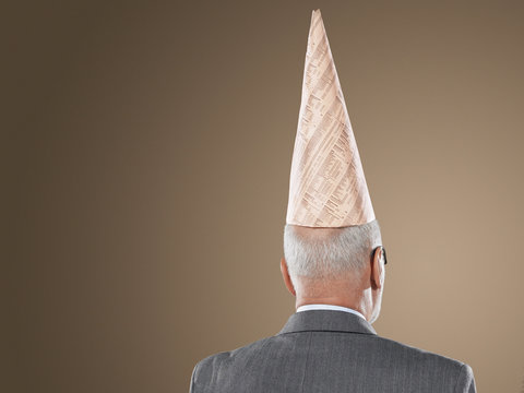 businessman wearing dunce hat back view head and shoulders