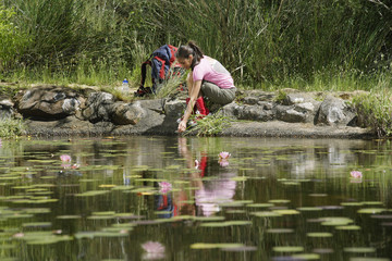 teenage girl (16-17 years) squatting by lake