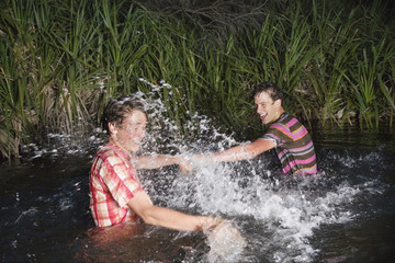 two teenage boys (16-17 years) messing about in water splashing