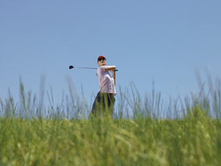 young female golfer driving ball low angle view