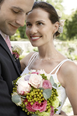 mid adult bride and groom holding bouquet smiling