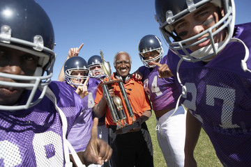 football coach and players holding trophy on field portrait (portrait)