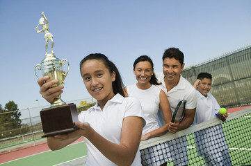 tennis family on court by net daughter holding trophy portrait