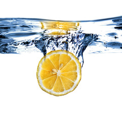 Fototapeta na wymiar Fresh lemon dropped into water with bubbles isolated on white