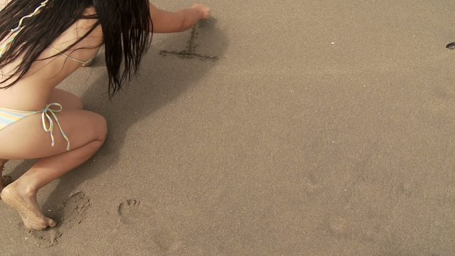 Frau schreibt in Sand: I LOVE YOU