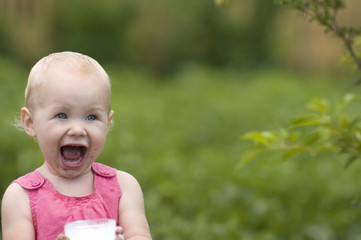 Laughing Baby Girl with glass of milk