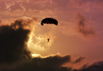 Parachutist against a colorful sunset and clouds.