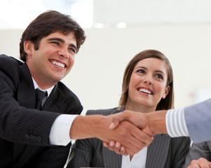 Smiling businessman and his colleague closing a deal with a part