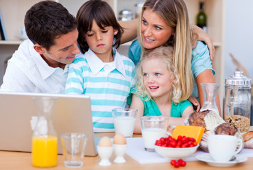 Obraz na płótnie Canvas Blissful family using laptop during the breakfast