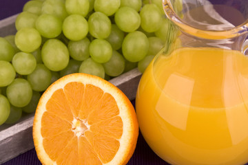 Orangensaft in einer Karaffe mit Orange und Weintrauben