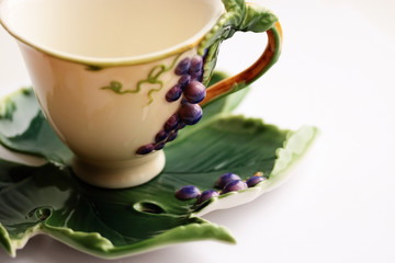 Porcelain tea cup and saucer with grapes ornament