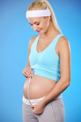 Pregnant woman measures her belly .