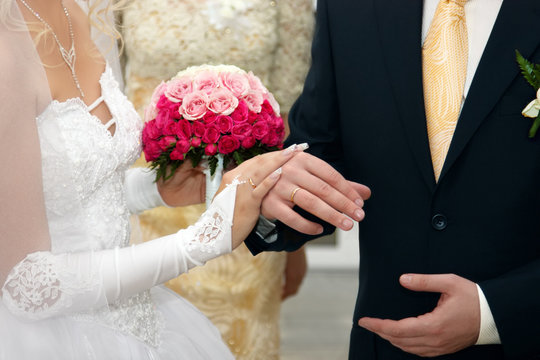 Bride And Groom Hands with Wedding Rings and Flowers