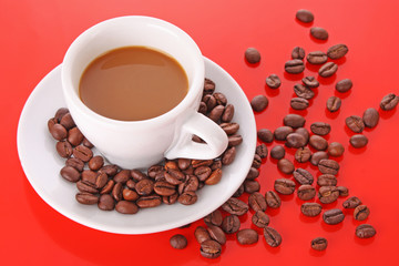 Small white cup of coffee with coffee grain on red background