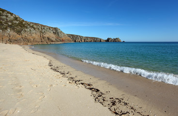 Porthcurno sandy beach shore line and Logan rock in Cornwall UK.