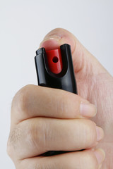 A woman's hand holding a small bottle of pepper spray