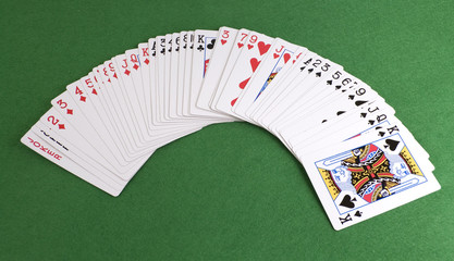 Baraja de poker extendida sobre tapete verde